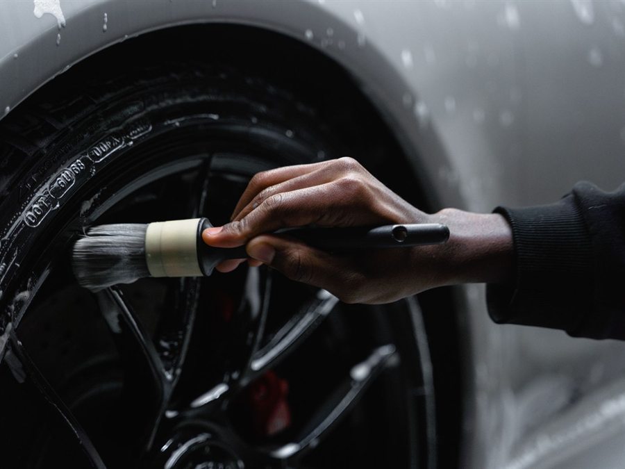 Wheel and tire being cleaned with a detail brush