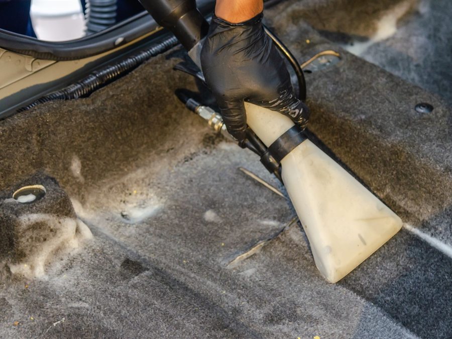 Car carpet being vacuumed and extracted during an interior detail