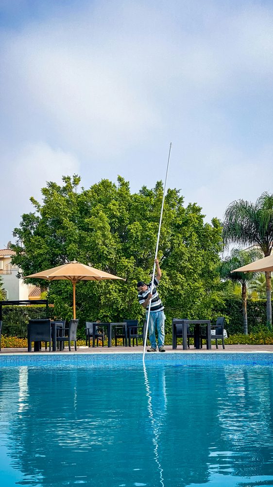 Pool technician skimming debris during a routine service visit